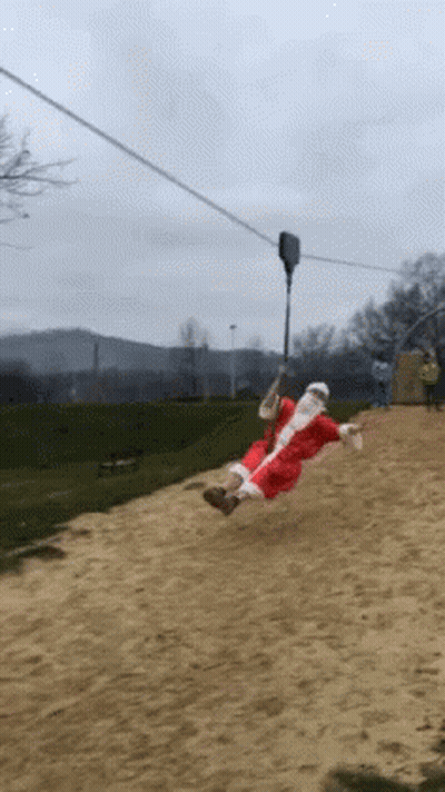 A Person Dressed As Santa Claus Is Riding A Zip Line GIF
