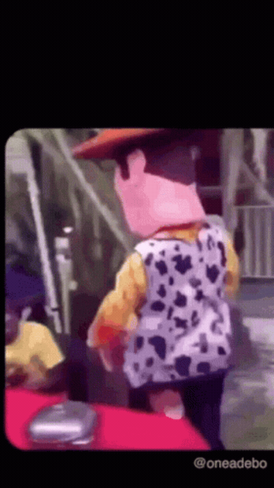 A Person Dressed As Woody From Toy Story Is Standing On A Red Carpet . GIF