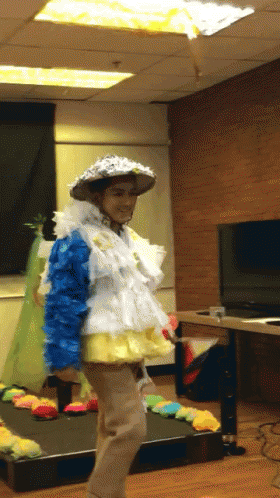 A Person Dressed In A Colorful Costume With A Hat On GIF