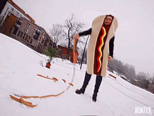 A Person Dressed In A Hot Dog Costume Is In The Snow GIF