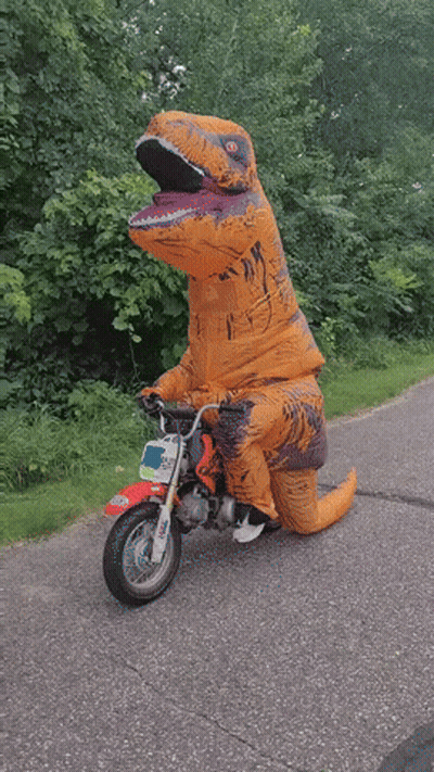 A Person Dressed In A T-Rex Costume Is Riding A Small Motorcycle GIF