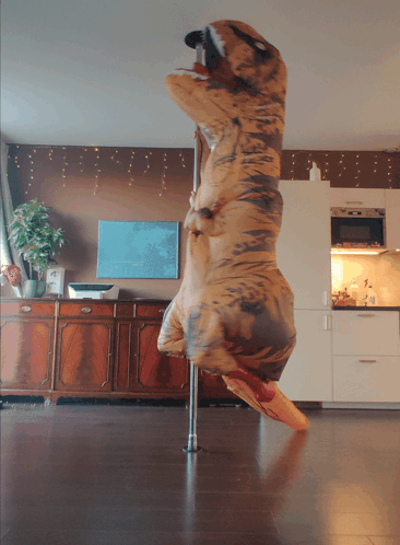 A Person Dressed In A T-Rex Costume Is Standing On A Pole GIF