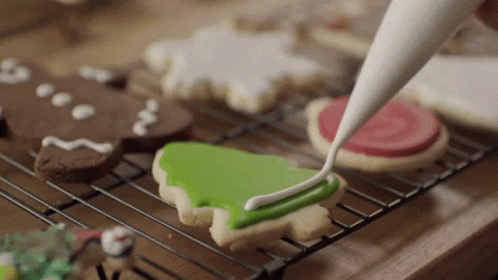 A Person Frosting A Cookie With Green Frosting GIF