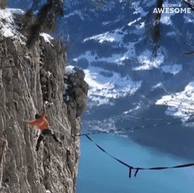 A Person Hanging From A Rope On A Cliff With The Words " Awesome " Above Them GIF