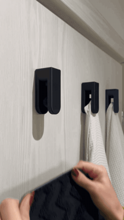 A Person Hangs A Towel On A Hook That Has The Letter U On It GIF