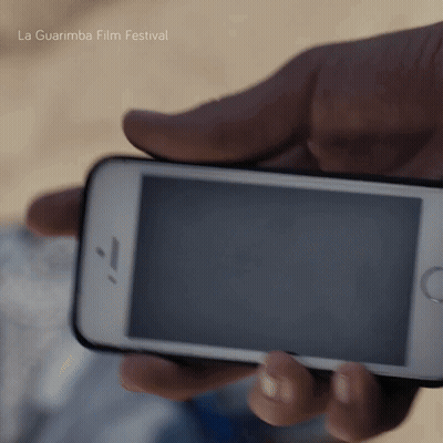 A Person Holding A Cell Phone With La Guarimba Film Festival Written In The Background GIF