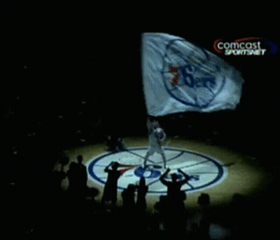 A Person Holding A Flag With A Comcast Logo On The Bottom Right GIF