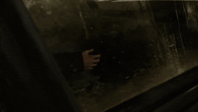A Person Holding A Gun In A Dark Room With A Blurred Background GIF