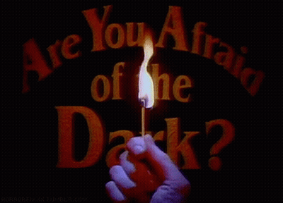 A Person Holding A Lit Match In Front Of A Sign That Says Are You Afraid Of The Dark GIF