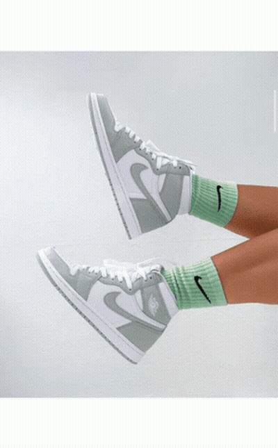 A Person Holding A Pair Of Green And White Nike Sneakers GIF