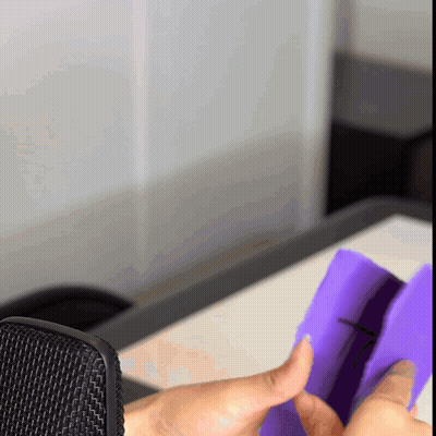 A Person Holding A Purple Object In Front Of A Black Microphone GIF
