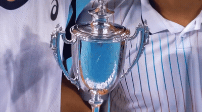 A Person Holding A Trophy In Front Of A Person Wearing A Shirt That Says Asics GIF
