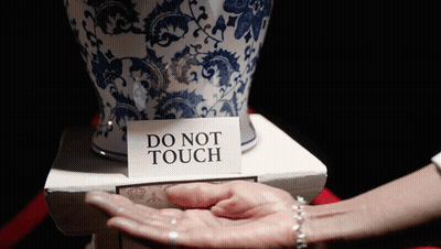 A Person Holding A Vase With A Do Not Touch Sign On It GIF