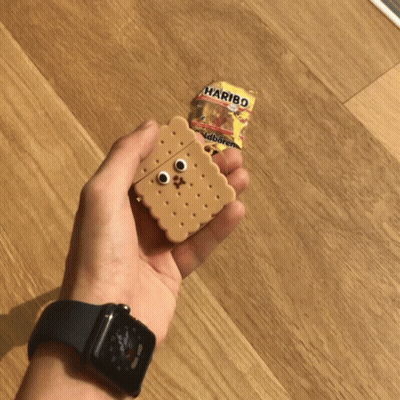 A Person Holding An Airpod Case In The Shape Of A Cookie Next To A Haribo Bag GIF