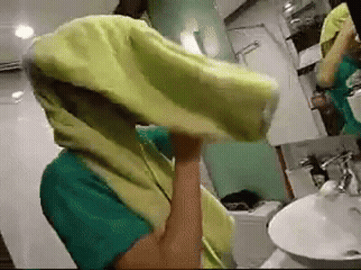 A Person In A Bathroom With A Yellow Towel On Their Head GIF