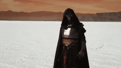 A Person In A Black Cape Is Standing In A Snowy Field . GIF