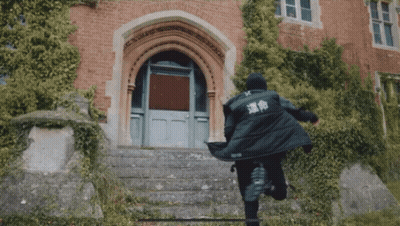 A Person In A Black Jacket With Chinese Writing On The Back Is Running Down Stairs GIF
