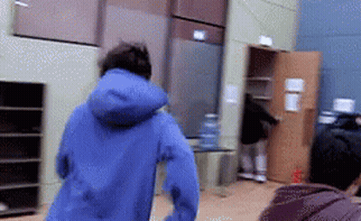 A Person In A Blue Jacket Is Running In A Room GIF