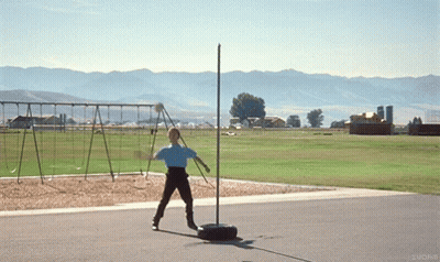 A Person In A Blue Shirt Is Throwing A Frisbee In A Field With Mountains In The Background GIF
