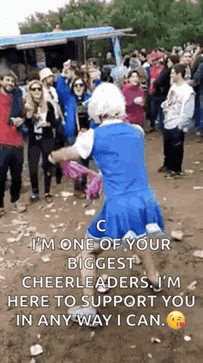 A Person In A Cheerleader Costume Is Dancing In Front Of A Crowd Of People . GIF