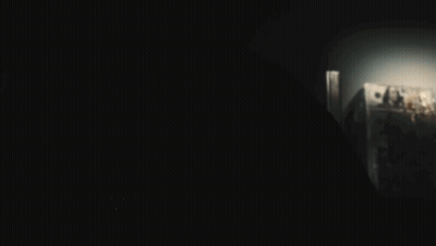 A Person In A Dark Room With A Light Shining On Their Face GIF
