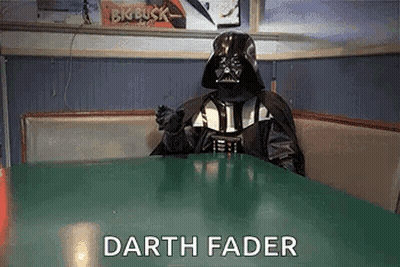 A Person In A Darth Vader Costume Is Sitting At A Table . GIF