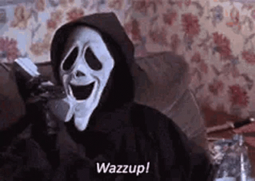 A Person In A Ghostface Mask Is Sitting On A Couch Holding A Cell Phone . GIF