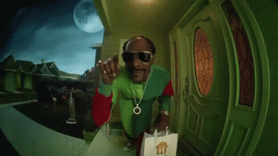 A Person In A Green Jacket Is Standing In Front Of A Door With A Bag In Front Of It GIF
