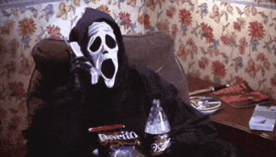 A Person In A Grim Reaper Costume Is Sitting On A Couch Talking On A Cell Phone GIF
