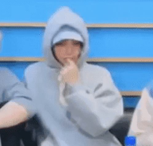 A Person In A Hoodie Is Eating A Banana . GIF