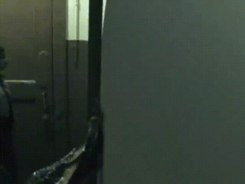 A Person In A Hoodie Is Standing In A Dark Room GIF