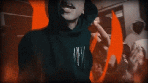 A Person In A Hoodie Is Standing In Front Of A Fire GIF