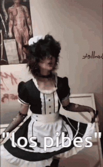 A Person In A Maid Costume Is Standing In Front Of A Wall With A Picture Of A Man On It . GIF
