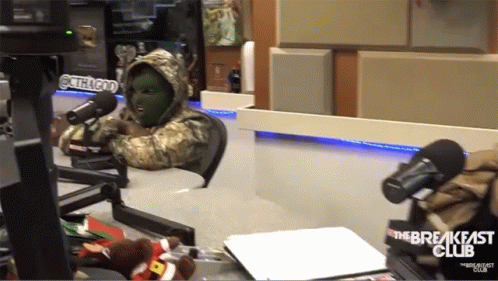 A Person In A Mask Is Sitting In Front Of A Microphone With The Breakfast Club Written On The Bottom GIF