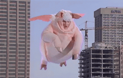 A Person In A Pig Costume Is Flying In The Air GIF