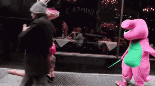 A Person In A Pink Costume Is Walking In Front Of A Carmines Restaurant GIF