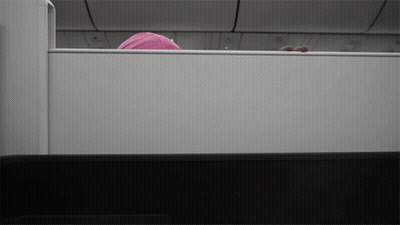 A Person In A Pink Hat Is Peeking Out From Behind A White Wall GIF
