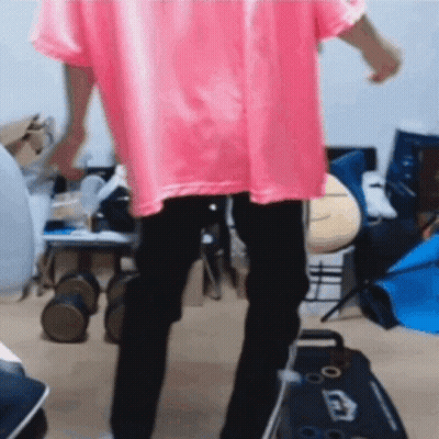 A Person In A Pink Shirt And Black Pants Is Dancing In A Room . GIF