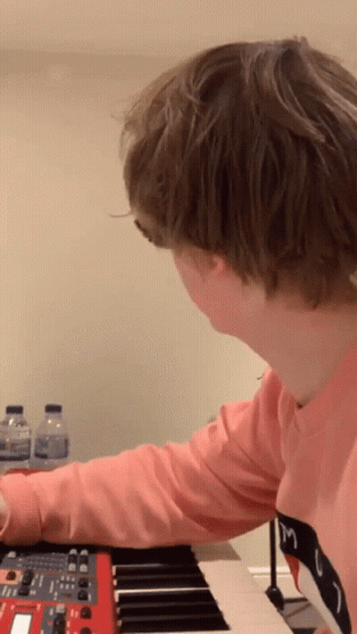 A Person In A Pink Shirt With The Letter M On It Is Playing A Keyboard GIF
