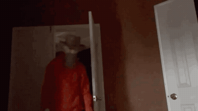 A Person In A Red Hoodie Is Standing In A Dark Room . GIF