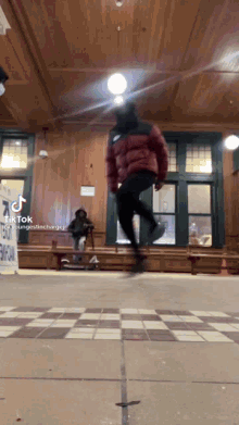 A Person In A Red Jacket Is Jumping On A Rope In A Room . GIF