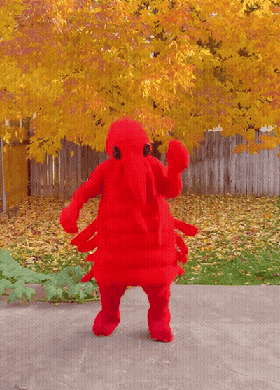 A Person In A Red Lobster Costume Is Dancing In Front Of A Fence GIF