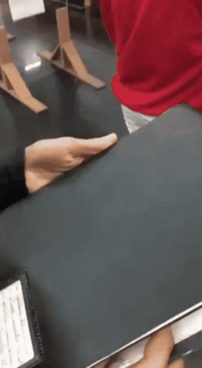 A Person In A Red Shirt Is Holding A Black Book In Their Hands . GIF