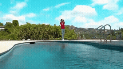 A Person In A Red Shirt Is Standing On The Edge Of A Swimming Pool . GIF