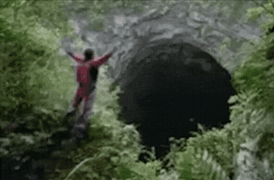 A Person In A Red Suit Is Standing In A Cave GIF