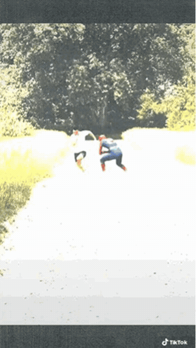 A Person In A Spiderman Costume Is Walking Down A Path GIF
