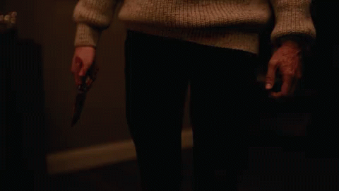 A Person In A Sweater Holding A Knife In Their Hand GIF
