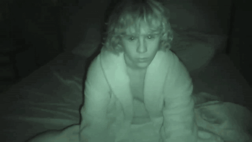 A Person In A White Robe Is Sitting On A Bed GIF