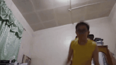 A Person In A Yellow Shirt Is Standing In A Room GIF