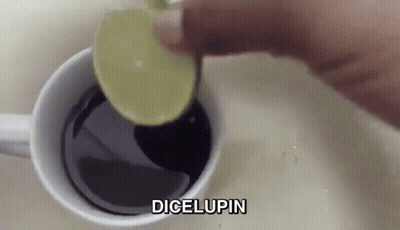 A Person Is Adding A Slice Of Lime Into A Cup Of Coffee . GIF